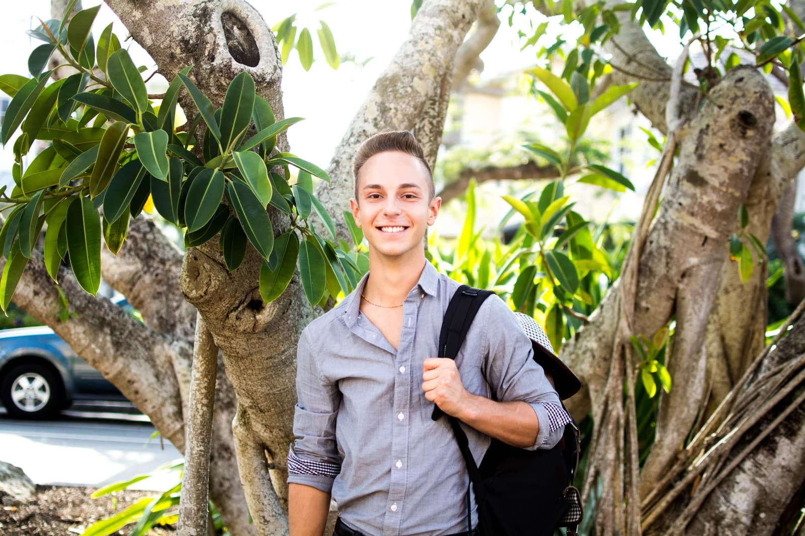 Jordan standing between the branches of a leafy tree.