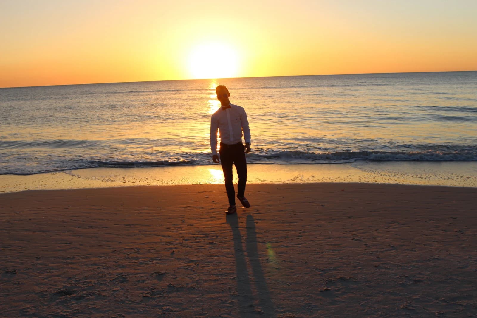 A figure on the beach as the sun sets over the Gulf in Naples.