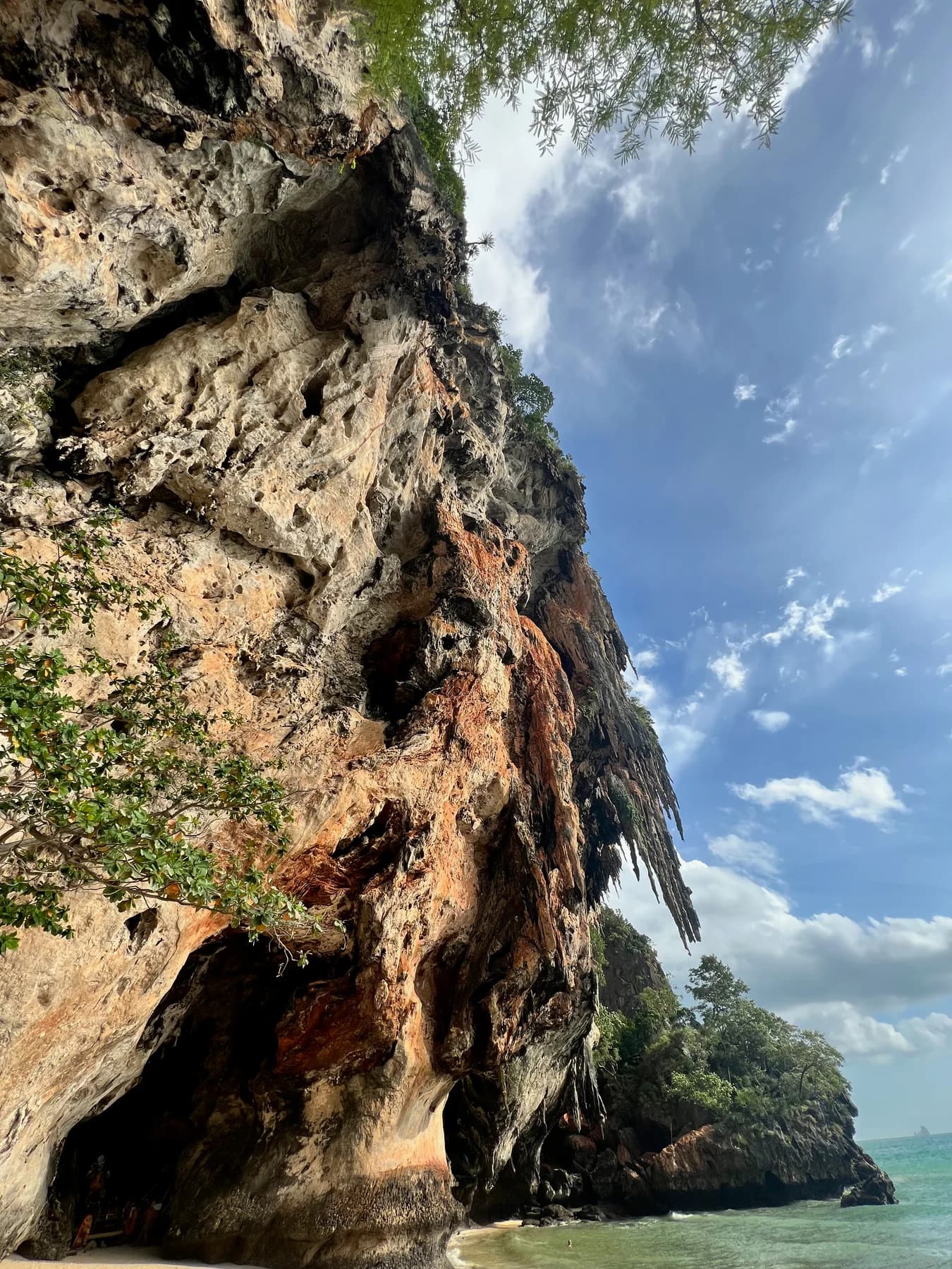 Looking up at a limestone cliff rising into the sky.